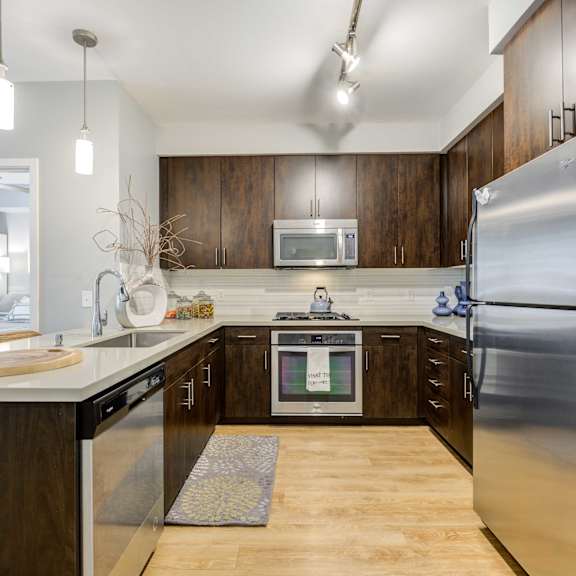 A modern kitchen with dark wood cabinets and stainless steel appliances.
