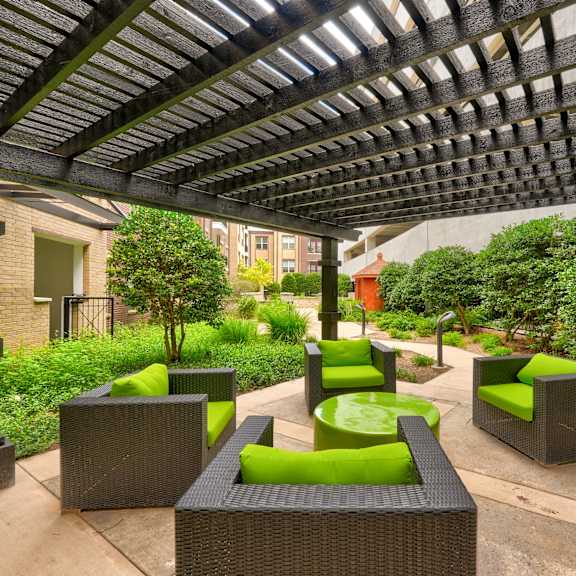 The covered courtyard with plush green chairs and a green coffee table surrounded by plants at the Edge at Midtown Apartment Homes. 