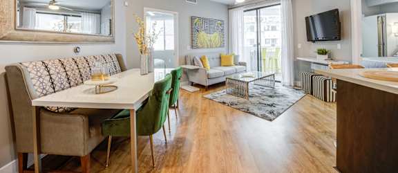A well-lit, spacious living room with a dining area and a kitchenette.