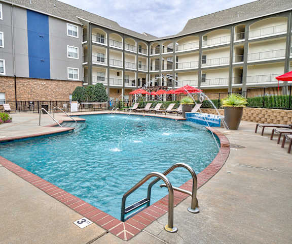 A swimming pool surrounded by pool chairs at Aviare Arts District Apartments. 