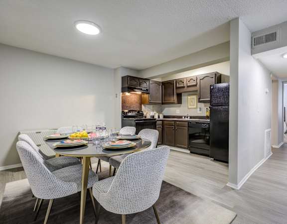 a dining area with a table and chairs and a kitchen in the background