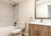 Thumbnail 12 of 14 - A white toilet sits next to a bathtub in a bathroom.