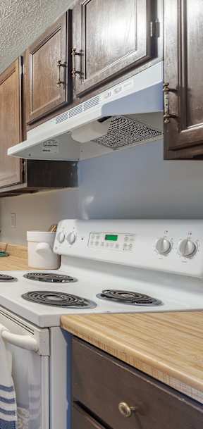 A kitchen with wooden cabinets and a white stove top oven.