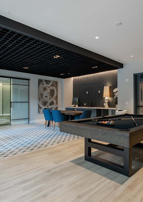 A room with a pool table and a bar area.
