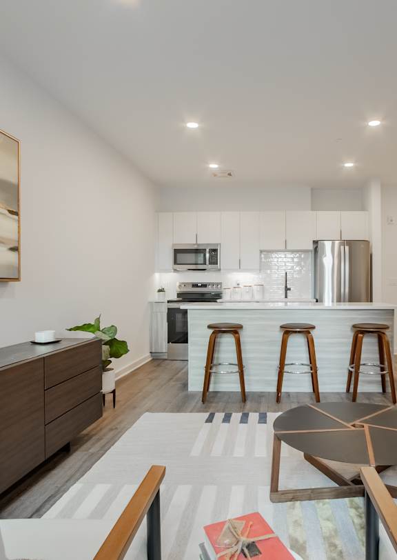 A modern living room with a kitchen in the background.