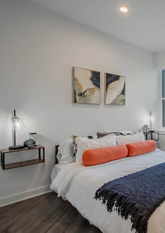 A bedroom with a large bed and two framed pictures on the wall.
