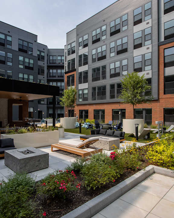 A courtyard with a fireplace and seating area surrounded by buildings.