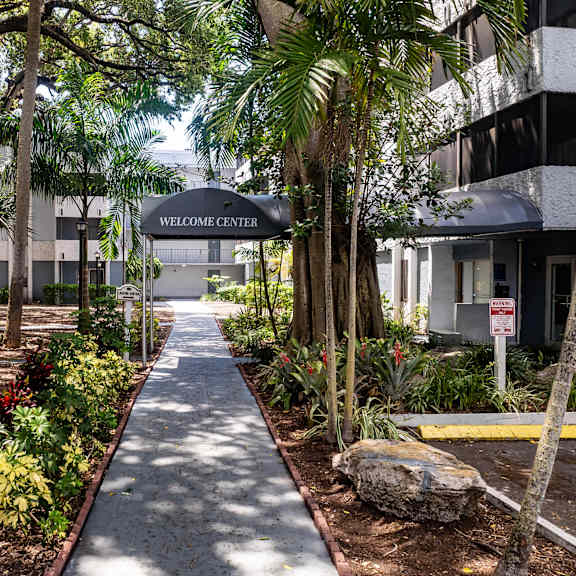 A pathway leads to a Welcome Center in a tropical setting.