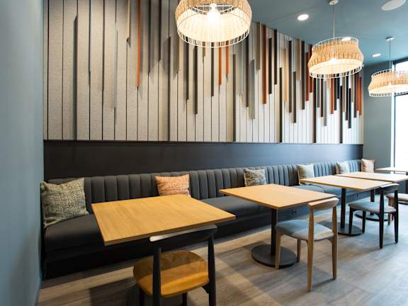 A modern dining area with a black booth and wooden tables.