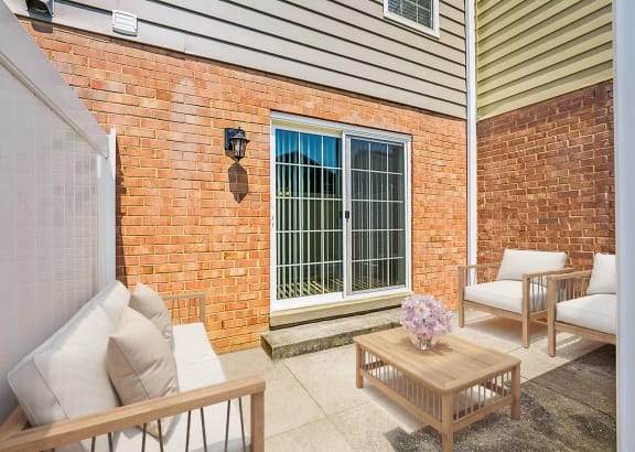 a patio with chairs and a table in front of a brick wall