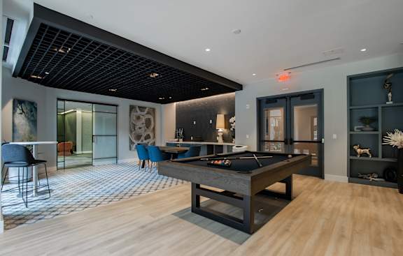 A room with a pool table and a bar area.