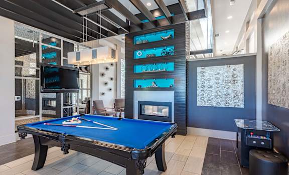 A pool table is in the middle of a room with a TV and a fireplace.