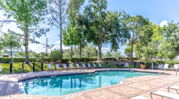 a pool with lounge chairs and trees in the background