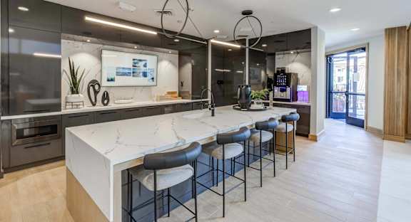 a large kitchen with a marble counter top and bar stools