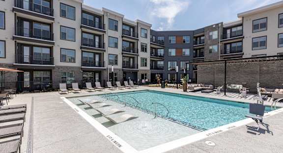 an apartment swimming pool in front of an apartment building