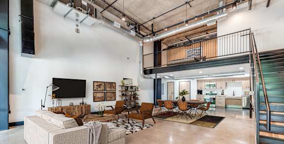 A living room with a couch, chairs, and a television.