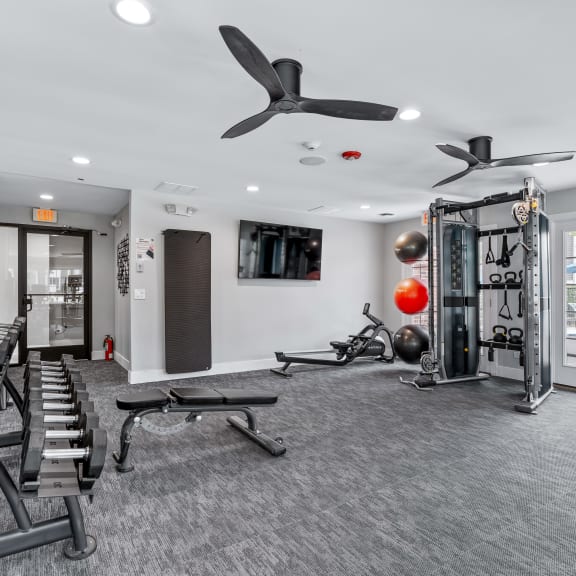 a gym with treadmills and other exercise equipment and a tv on the wall