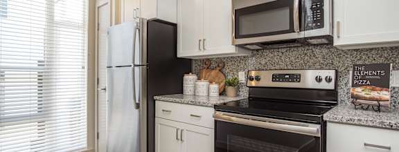 A kitchen with white cabinets and black appliances. at Liberty Square Apartments - Saltlake City, UT Apartments, Saltlake City, Utah
