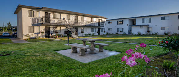 A building with a balcony and a patio table surrounded by flowers.