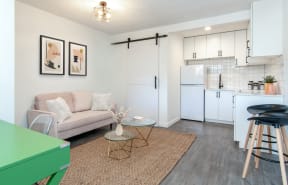 The Imperial Apartments Model Studio with Couch, Bathroom Door, and Kitchen