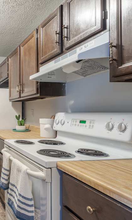 A kitchen with wooden cabinets and a white stove top oven.