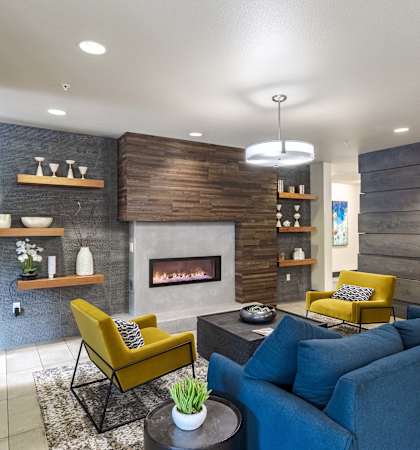 a living room with a blue couch and yellow chairs and a fireplace