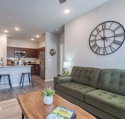 A living room with a green couch and a clock on the wall.