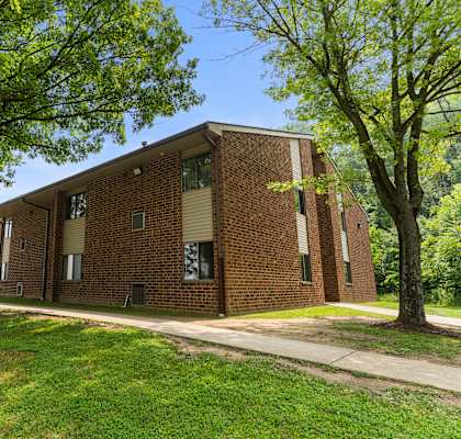 a large brick building with trees in front of it at Belvedere Acres Apartments, Washington, 15301