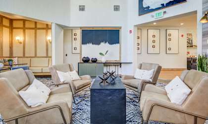 A living room with beige chairs and a black coffee table.