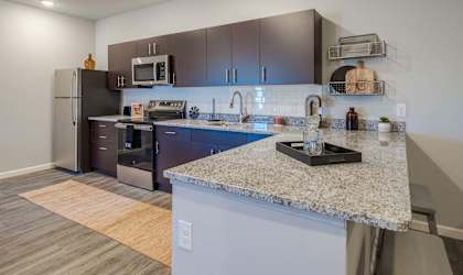 A kitchen with a granite counter top and stainless steel appliances.