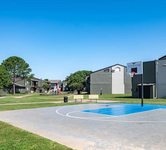 a basketball court in a park with houses in the background