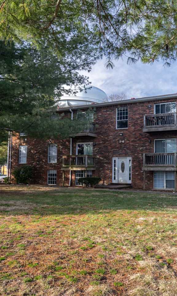 A brick apartment building with a green lawn in front.