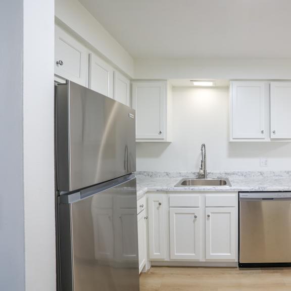 A kitchen with white cabinets and a stainless steel refrigerator.