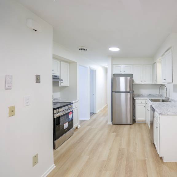 A kitchen with white cabinets and a stainless steel refrigerator.