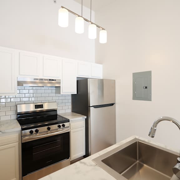A kitchen with a stove, refrigerator, and sink.