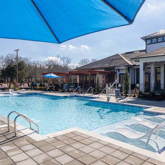 A large outdoor swimming pool with a blue umbrella.