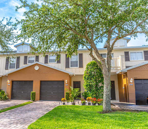 a house with two garages and a tree in front of it
