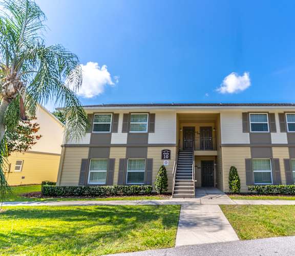 an apartment building with a sidewalk in front of it and a palm tree on the side of