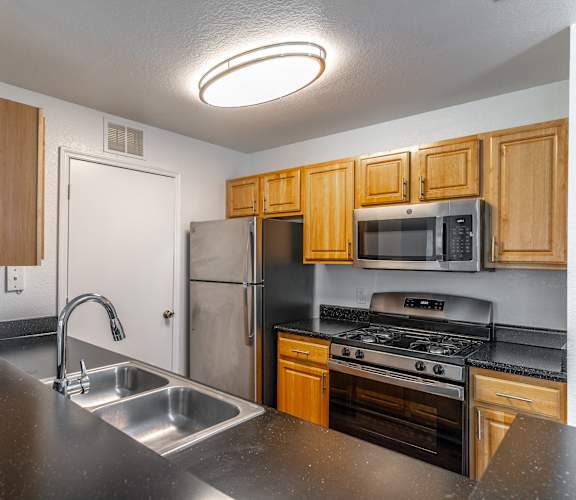 a kitchen with wood cabinets and black countertops