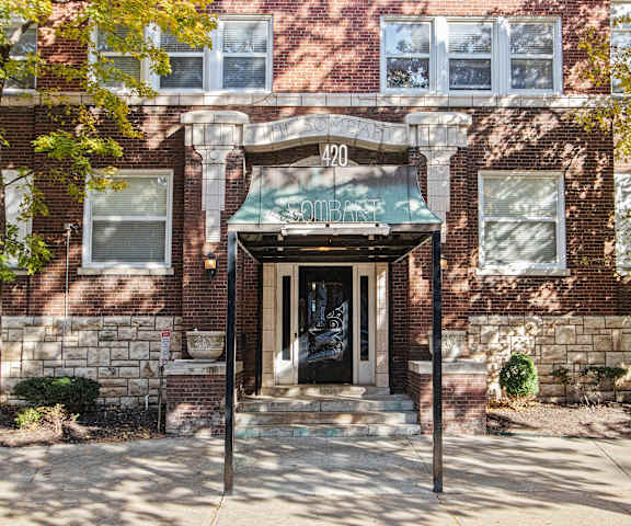 A red brick building with a green awning and a black door.
