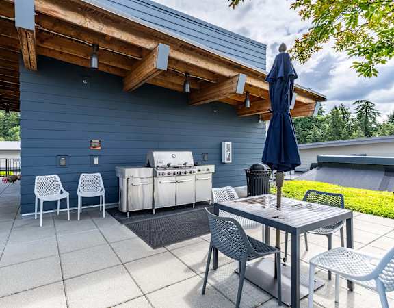 the patio has an outdoor grill and table with chairs and an umbrella