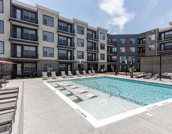 an apartment swimming pool in front of an apartment building