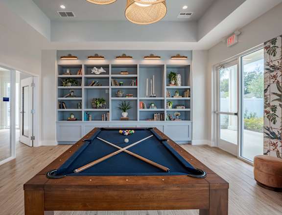 a pool table in a living room with a bookshelf
