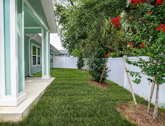 a yard in front of a house with a lawn and trees