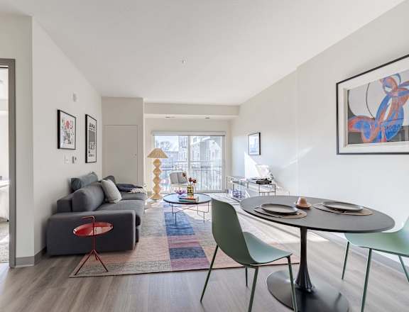 A modern living room with a grey couch, a red chair, a green chair, and a round table.