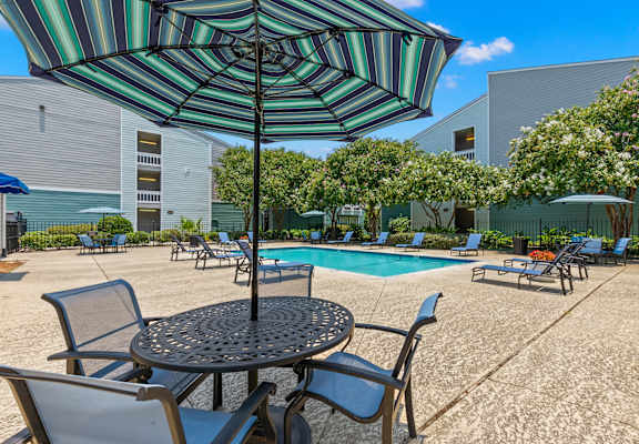 A patio with a table, chairs and an umbrella.