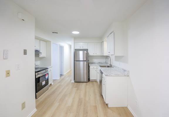 A kitchen with white cabinets and a stainless steel refrigerator.