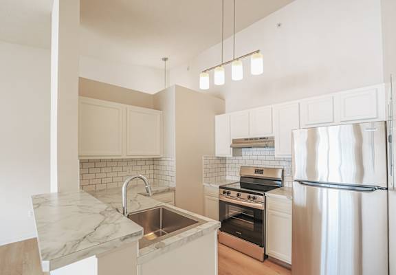 A kitchen with a marble countertop and stainless steel appliances.