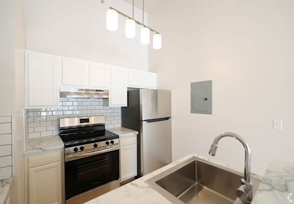 A kitchen with a stove, refrigerator, and sink.