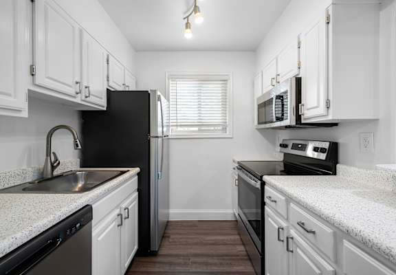a kitchen with white cabinets and black appliances